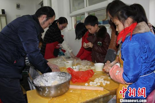 图为，低年级学生在家长帮助下学习包饺子 徐金波 摄