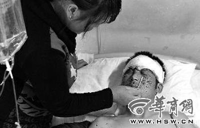 吕某躺在病床上，妻子用药水为他清洁面部伤口本报记者张杰摄